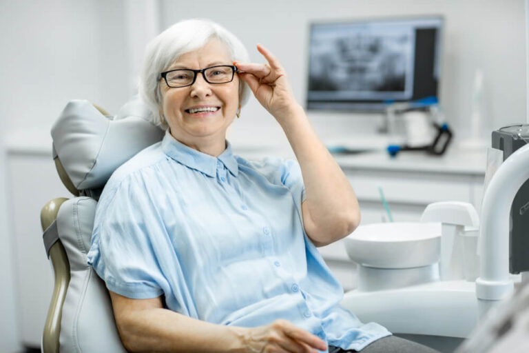 a old lady is holding her specs while getting dental treatment