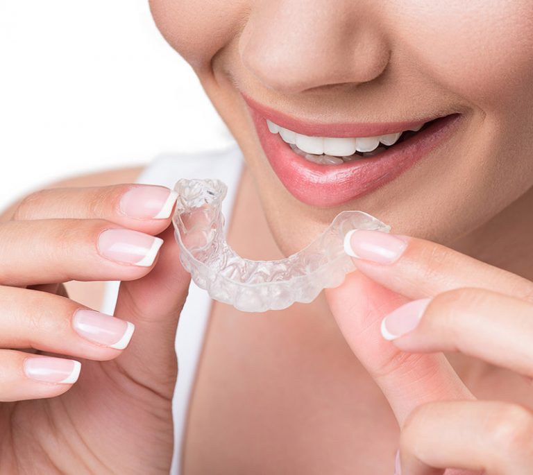 a lady is holding invisalign before putting on her mouth